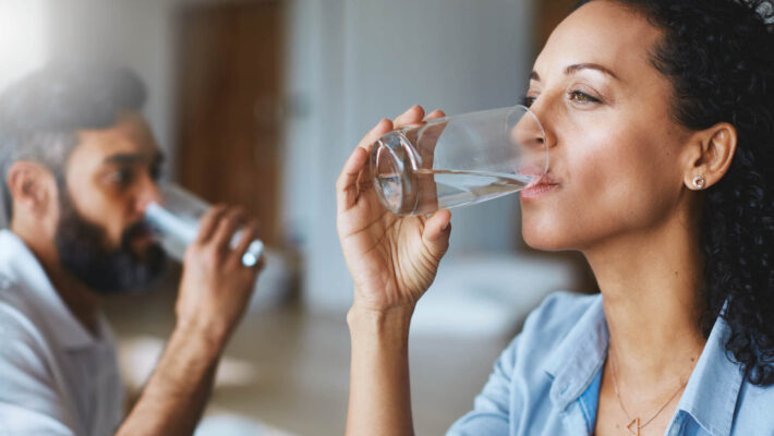 Paar trinkt Wasser - Zu viel abgebauter Kalk im Körper - Symptome