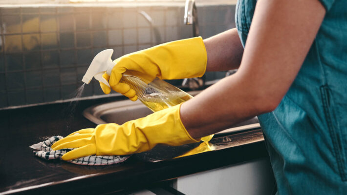 Ausschnitt einer nicht erkennbaren Frau, die ihre Küche zu Hause mit haushalts-Kalk-Reinigungsmittel säubert