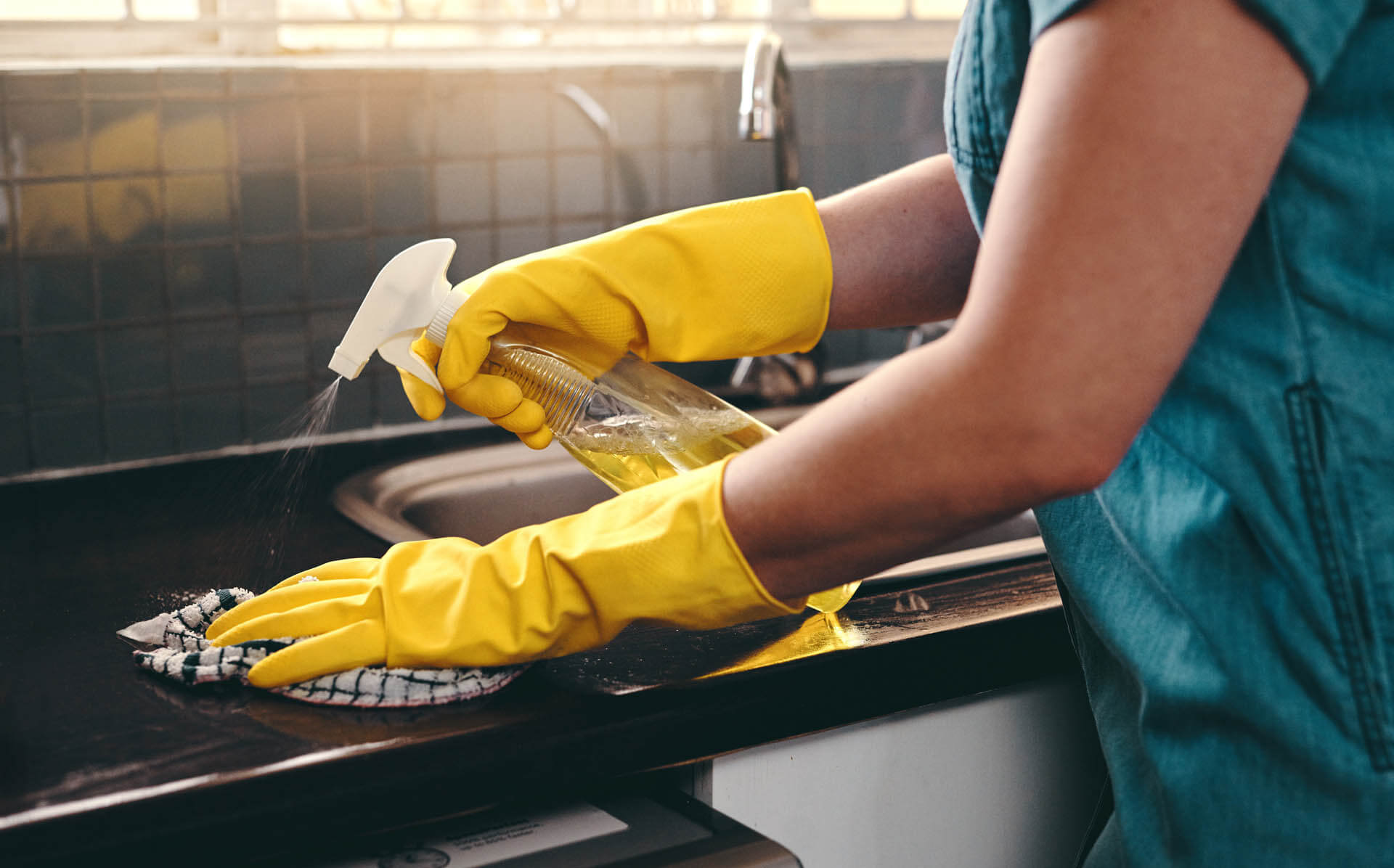 Ausschnitt einer nicht erkennbaren Frau, die ihre Küche zu Hause mit haushalts-Kalk-Reinigungsmittel säubert