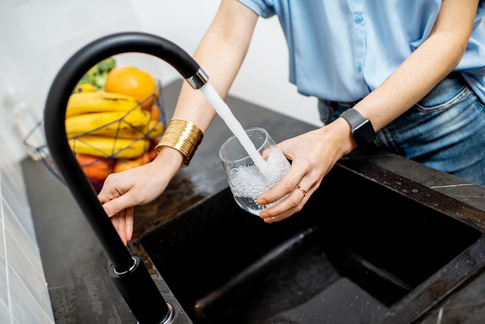 Frau füllt Leitungswasser von dem Wasserhahn in der Küche ab nicht vom Wasserkocher