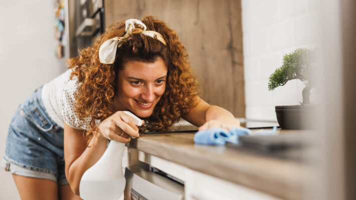 Frau macht Hausarbeiten zuhause in Küche und Armaturen, putz mit alternativem Kalkschutz