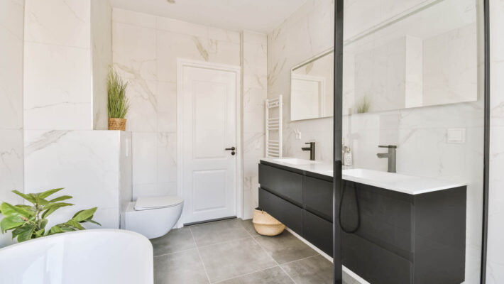 Interieur eines modernen hellen Badezimmers mit Toilette und kalkbereinigter Duschkabine mit Plexiglas