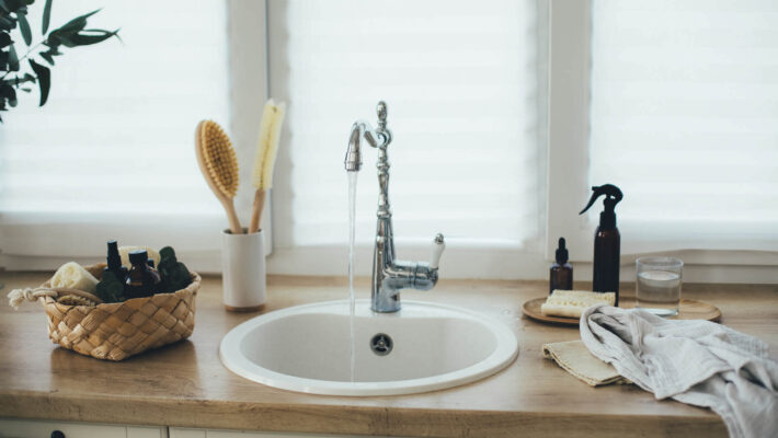 Kücheneinrichtung mit natürlichen, umweltfreundlichen, plastikfreien Reinigungsmitteln gegen Kalk und einem weißen Waschbecken