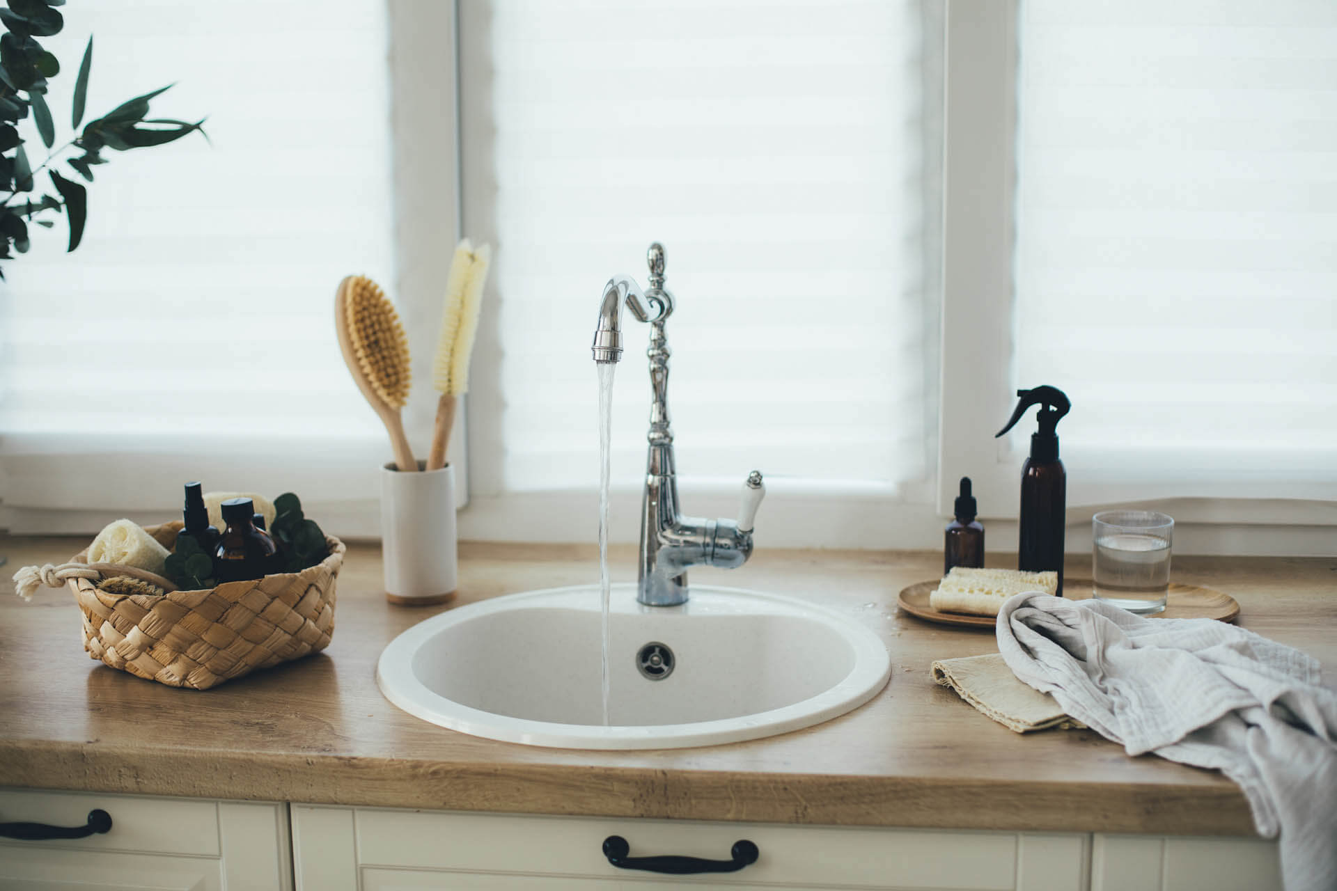 Kücheneinrichtung mit natürlichen, umweltfreundlichen, plastikfreien Reinigungsmitteln gegen Kalk und einem weißen Waschbecken