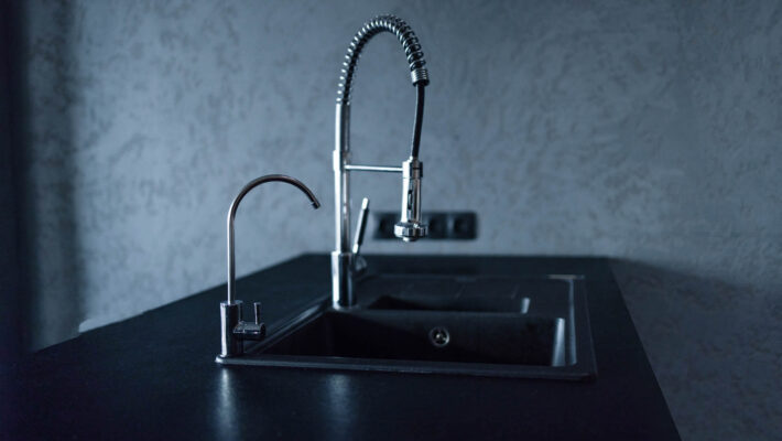 Küchenspüle und Wasserhahn auf schwarzer Küche - Inneneinrichtung - schwarze Spüle mit Kalk