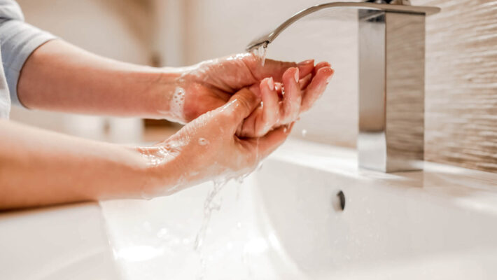 Mädchen wäscht sich im Badezimmer die Hände mit Seife und Kalk im Wasser