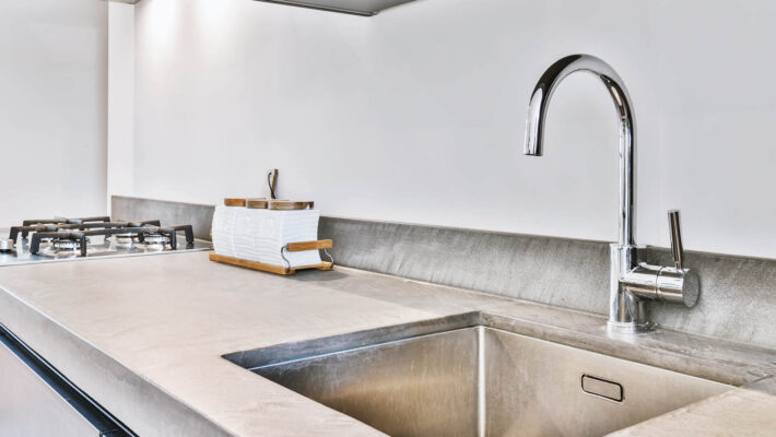 Modernes Waschbecken mit einigem Kalk unter der Theke in der Küche, mit Wasserfilter Kalk Wasserhahn