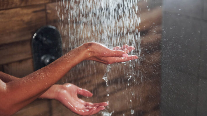 Nahaufnahme der Hände einer Frau, die eine Dusche mit Kalk imm Wasser im Spa nimmt, da sie in ihrem Einfamilienhaus eine Enthärtungsanlage haben