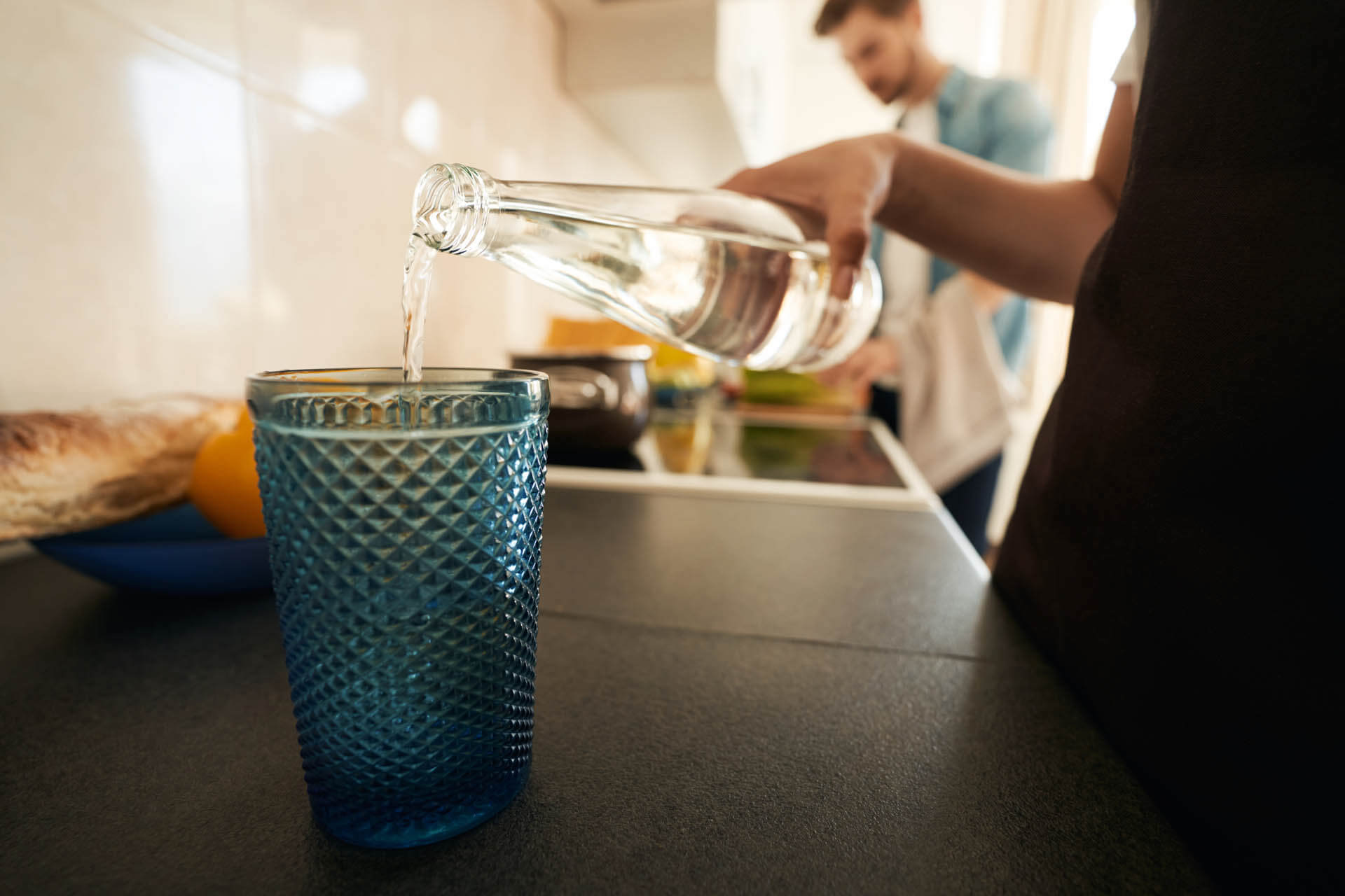 Pärchen an der Küchentheke bei der Essenszubereitung stehend und Wasser trinkend mit Geschmack da Kalk dabei ist sie keine Kalk im Wasser