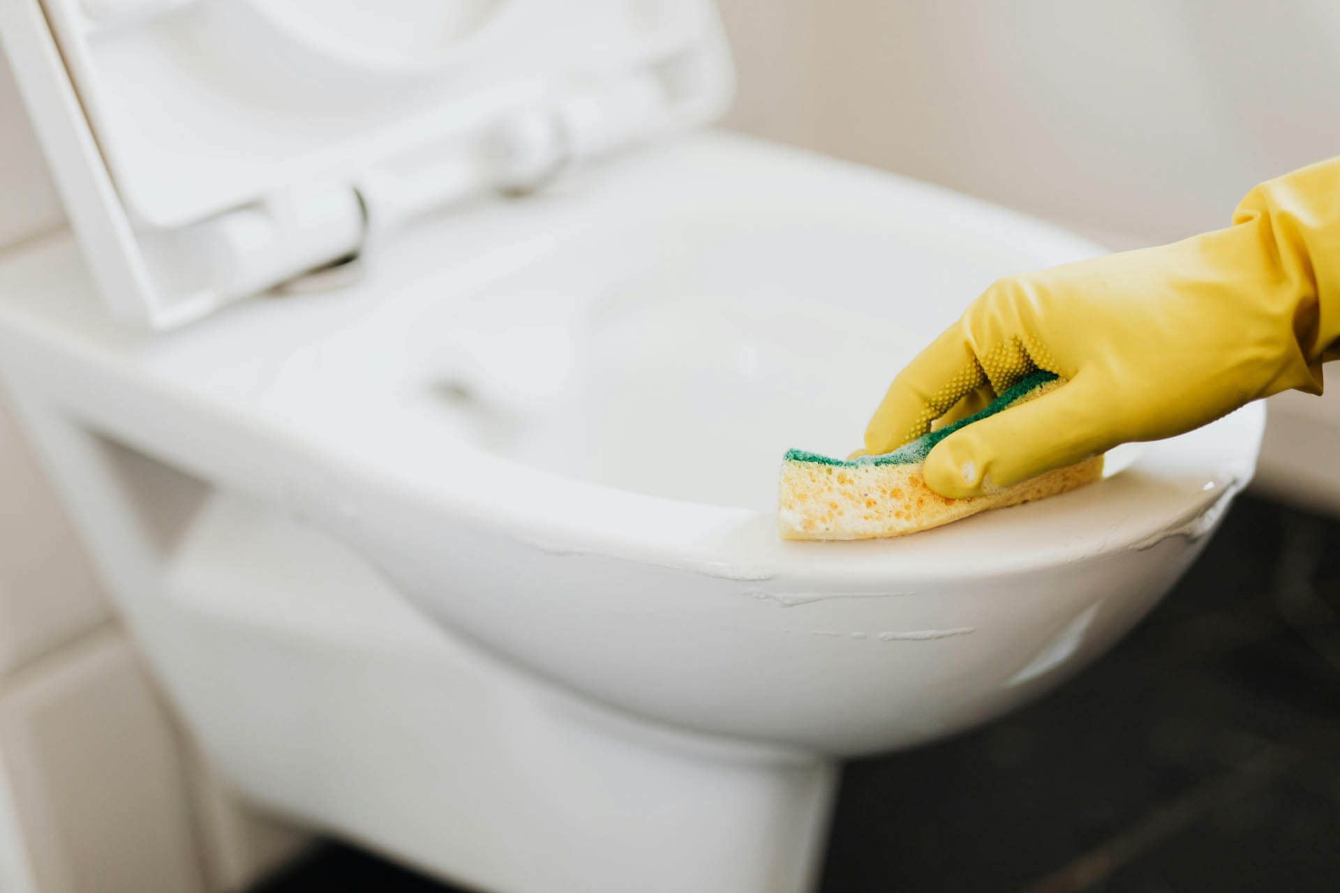 WC von Kalk entfernen mit Handschuh und ist dabei Eingefressener Kalk entfernen