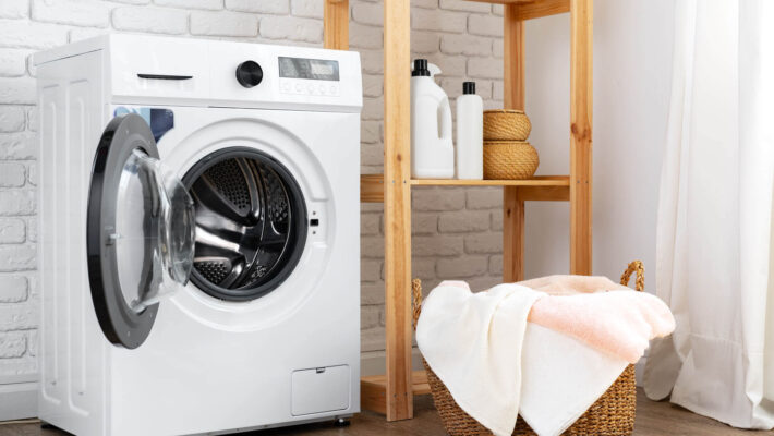 Waschküche mit Waschmaschine, Waschmittel mit Kalkschutz und Korb mit Wäsche